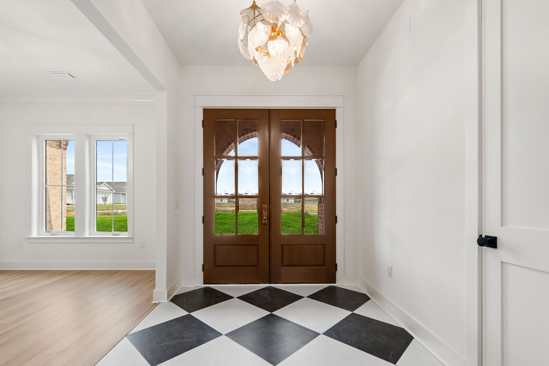 Foyer with arched wood double doors and checkerboard floor in an AJAC Group custom home