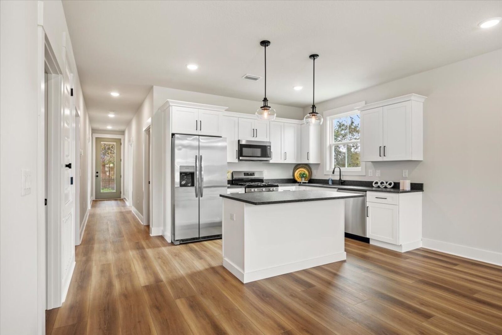 Kitchen island with dark countertops and white cabinetry in an AJAC Group home
